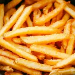 A close-up of crispy golden French fries inside an air fryer basket, perfectly cooked and ready to serve.