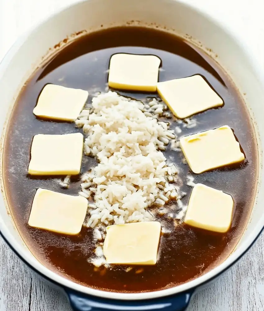 features a close-up of "stick of butter rice," showcasing a spoonful of fluffy, golden-brown rice with crispy bits. The bowl in the background is filled with the buttery, caramelized dish, creating a cozy and appetizing presentation.