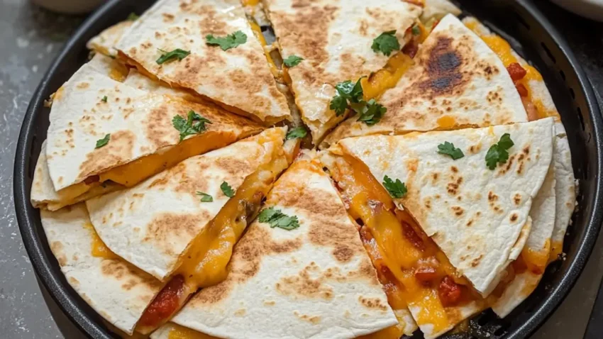 Golden-brown air fryer quesadilla sliced into triangles, filled with melted cheese and garnished with fresh cilantro, served on a black plate.