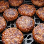 Close-up of golden-brown sausage patties cooked in an air fryer basket.