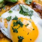 Close-up of a fried egg taco topped with fresh cilantro, sliced avocado, melted cheese, and savory salsa.