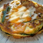 Close-up of crispy golden scallion pancakes topped with a drizzle of syrup, served on a ceramic plate.