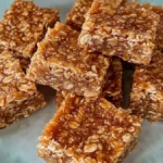 Close-up of golden buttery flapjack oat bars stacked on a light blue plate.