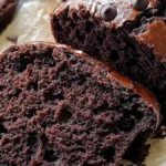 Close-up of freshly baked chocolate chip bread, sliced to reveal its moist and rich chocolate interior, topped with glossy chocolate chips.