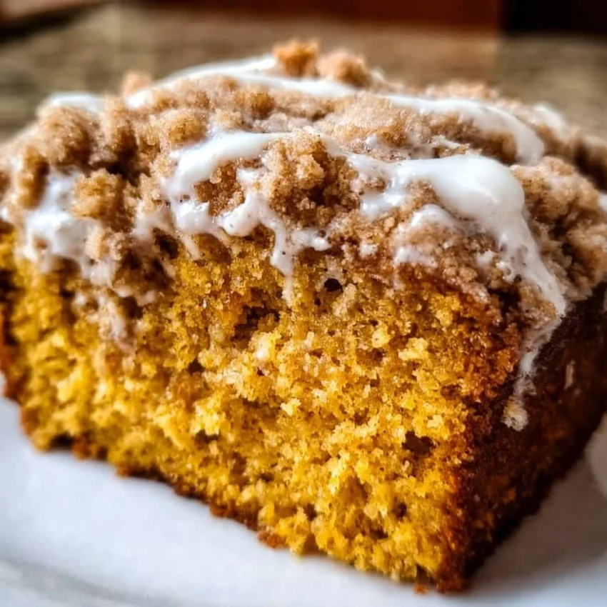 Delicious slice of pumpkin coffee cake topped with cream, perfect for autumn.
